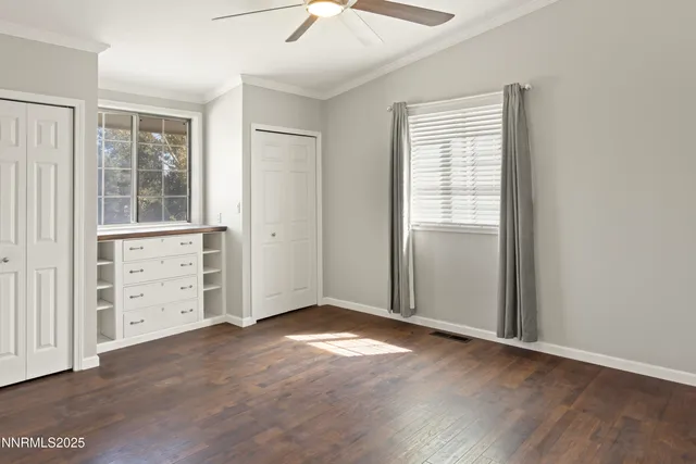 an empty room with windows closet and chandelier fan