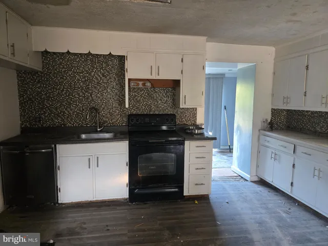 a kitchen with granite countertop white cabinets and black appliances