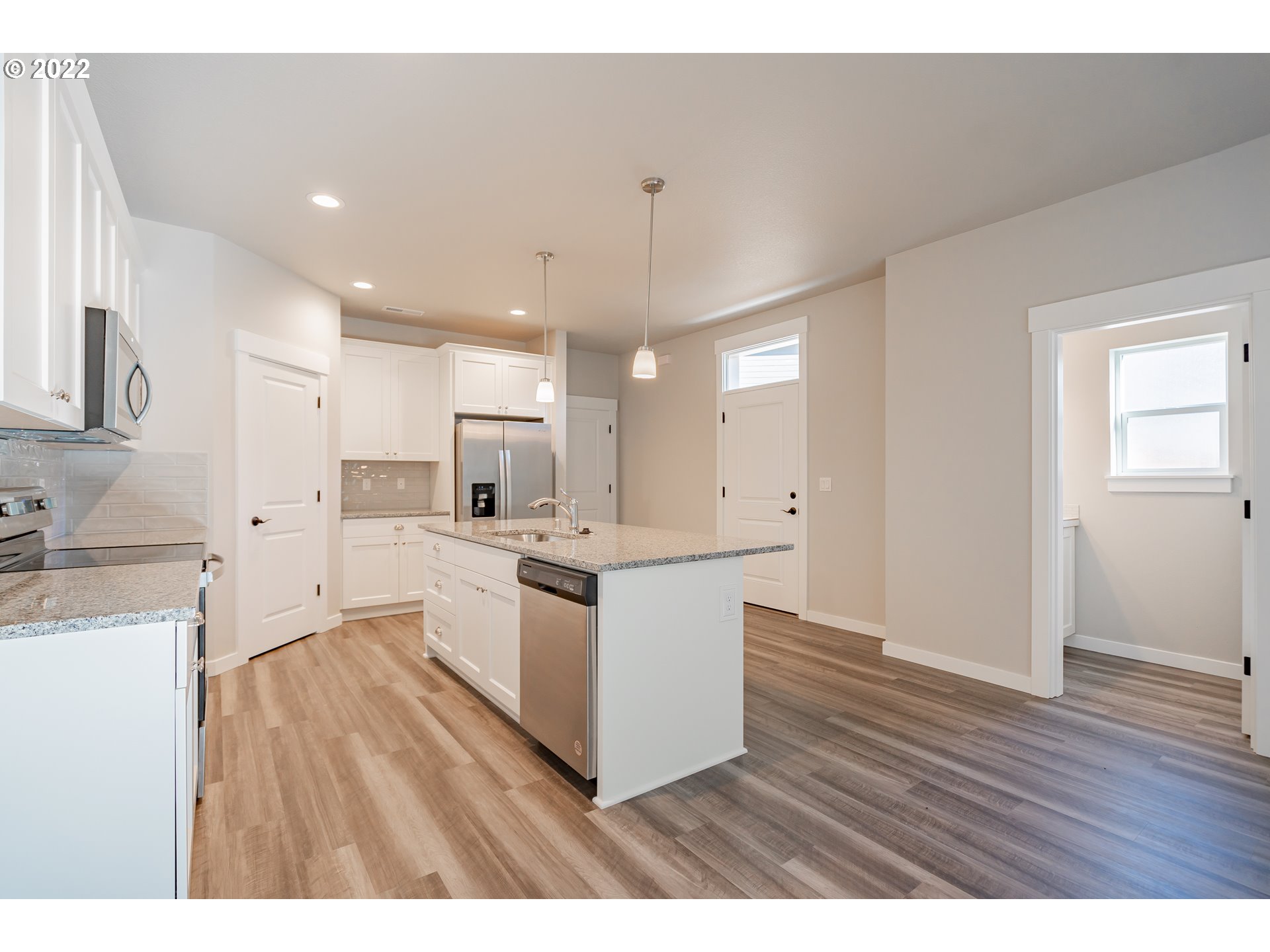 7225 South 13th Street Ridgefield, WA 98642 - Photo 4 of 30 a large white kitchen with a refrigerator a sink dishwasher and a stove with wooden floor