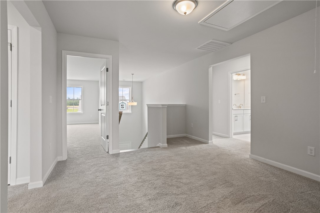 555 Hydrangea Street, Unit LOT 47 Seneca, SC 29678 - Photo 20 of 38 A well-lit landing area offers a seamless transition between rooms, showcasing soft carpeting and a glimpse of an adjacent bath.