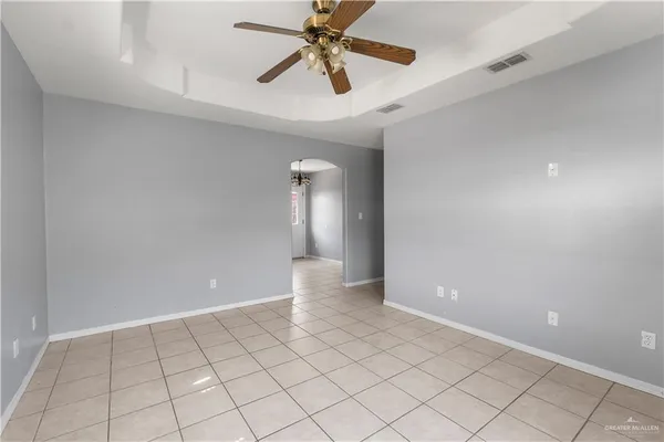 a view of an empty room and chandelier fan