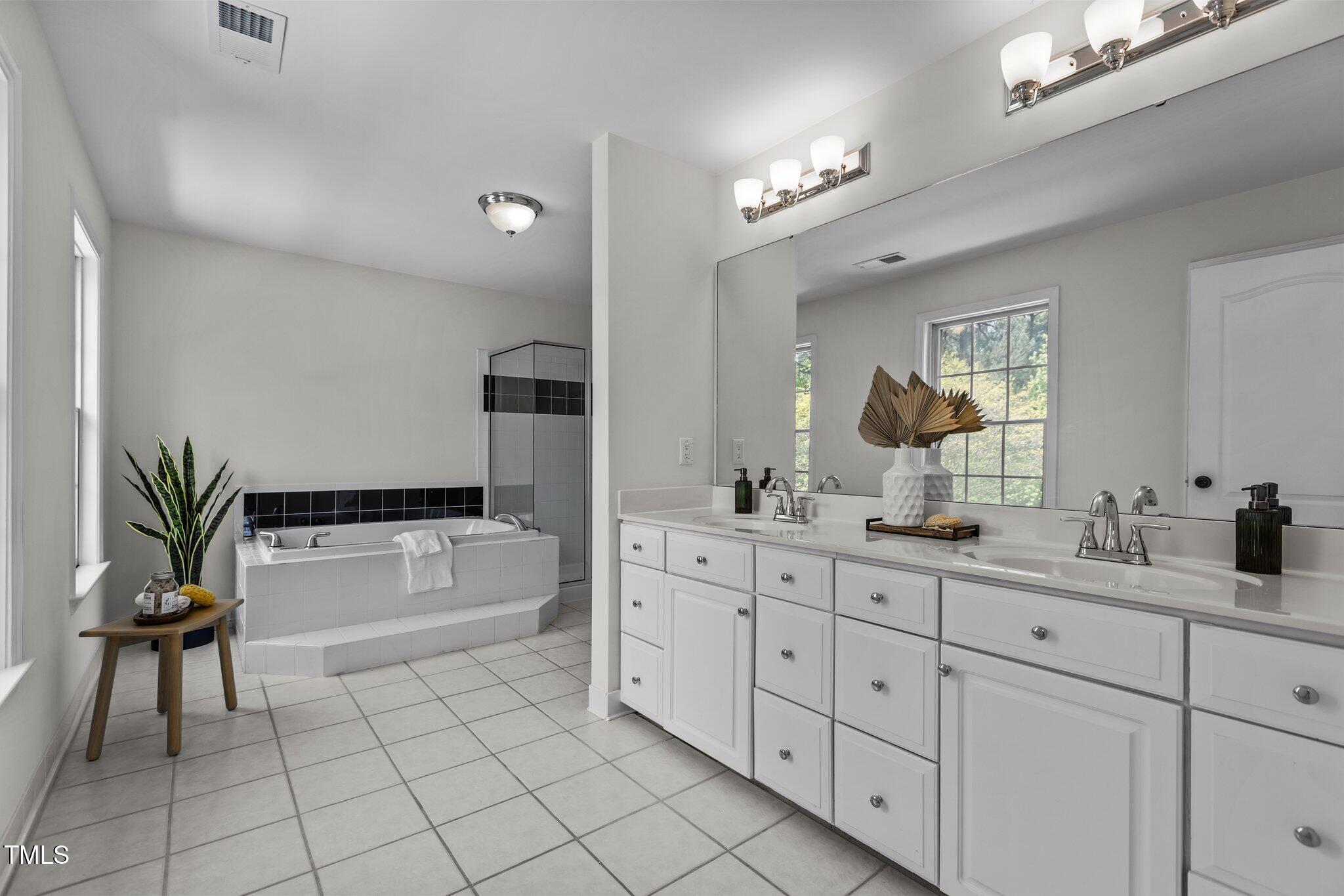 103 Ticonderoga Road Cary, NC 27519 - Photo 31 of 65 a spacious en suite bathroom with double vanity a bathtub and a double vanity