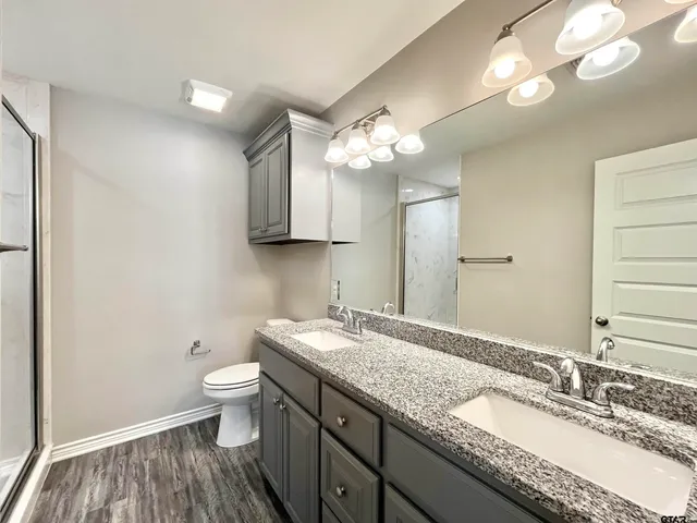 a bathroom with a granite countertop double vanity sink and a mirror