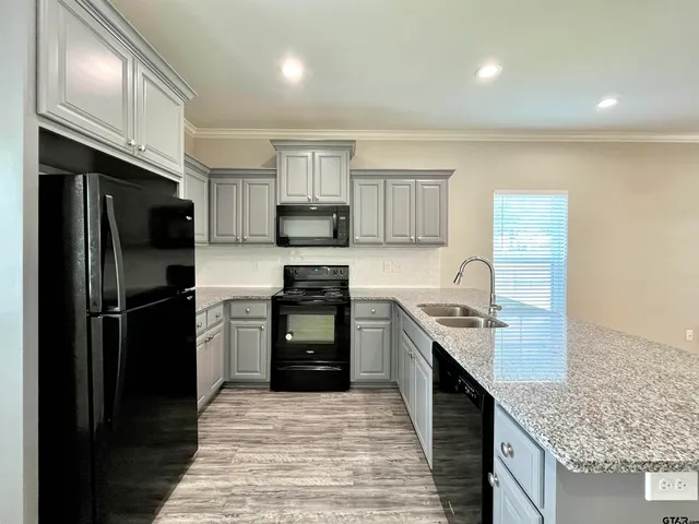 a kitchen with stainless steel appliances granite countertop a refrigerator a stove a sink and a microwave