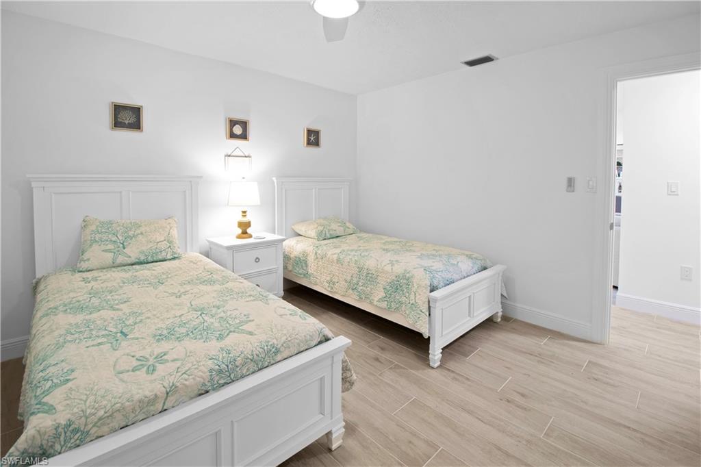 19 East Pelican Street Naples, FL 34113 - Photo 18 of 50 a bedroom with two beds and a night stand with wooden floor