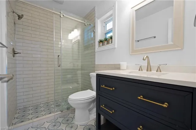 a bathroom with a sink a toilet a mirror and shower