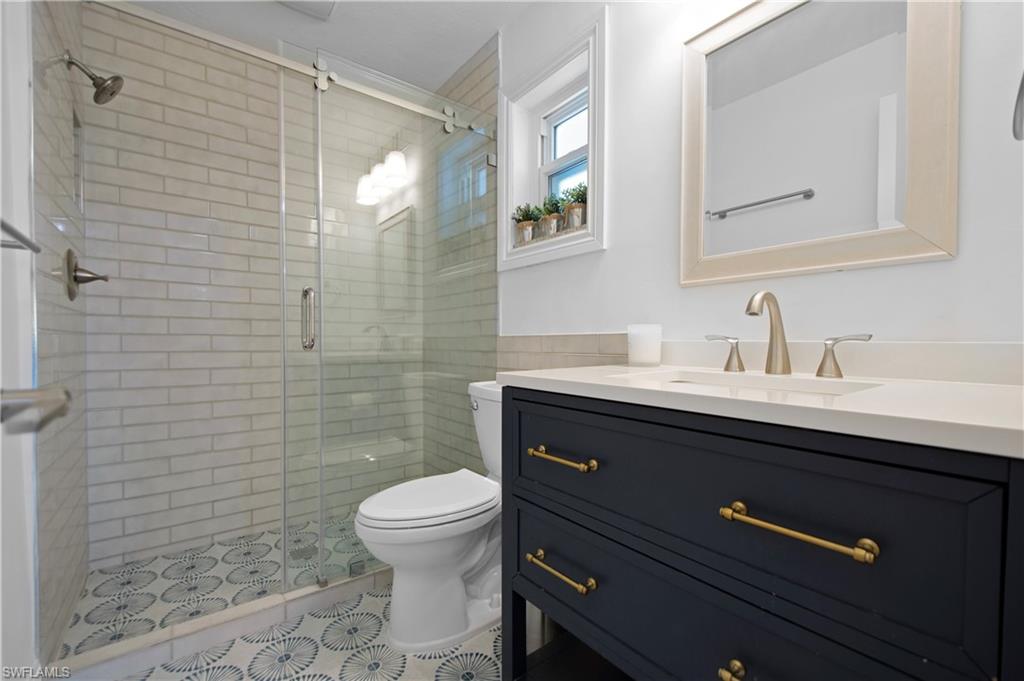 19 East Pelican Street Naples, FL 34113 - Photo 20 of 50 a bathroom with a sink a toilet a mirror and shower