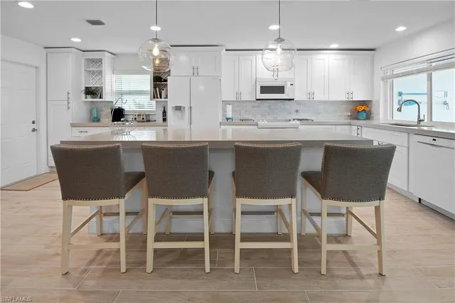 a kitchen with a dining table chairs cabinets wooden floor and appliances