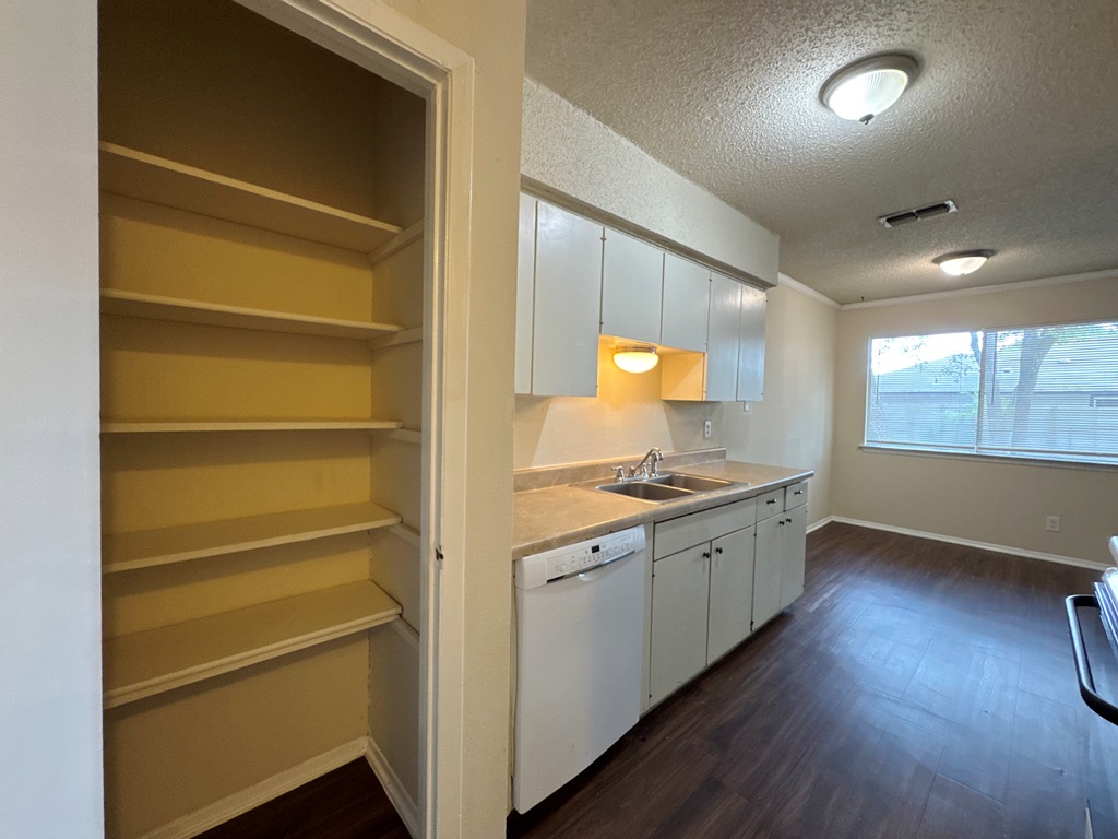 5905 Burrough Drive Austin, TX 78745 - Photo 17 of 40 Kitchen with dark wood-style flooring, light countertops, a textured ceiling, white cabinets, and dishwasher