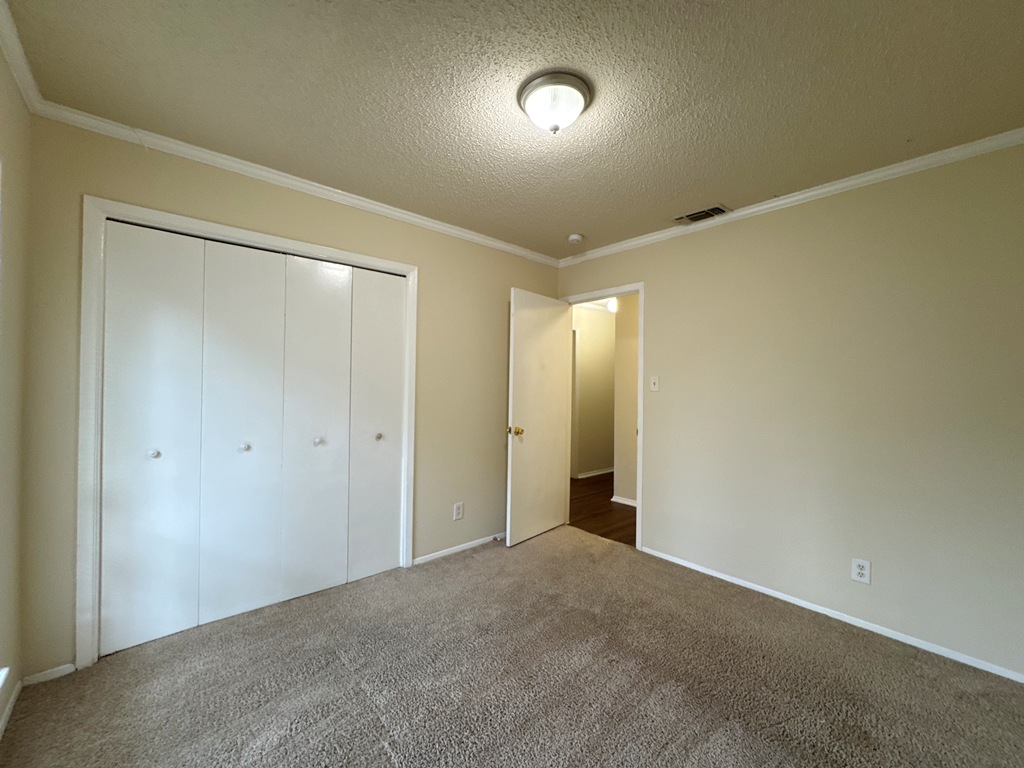 5905 Burrough Drive Austin, TX 78745 - Photo 21 of 40 Unfurnished bedroom with crown molding, carpet flooring, a textured ceiling, and a closet