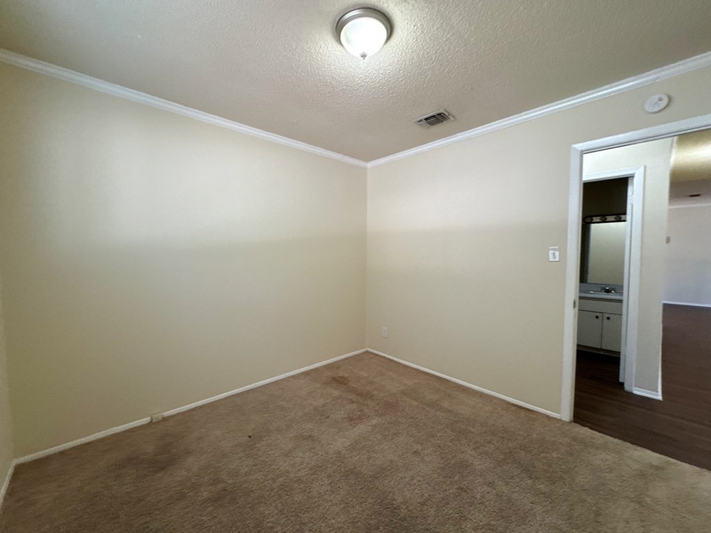 5905 Burrough Drive Austin, TX 78745 - Photo 29 of 40 Unfurnished room with ornamental molding, a textured ceiling, and dark colored carpet