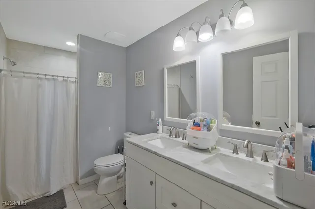 a bathroom with double vanity sink a toilet and a mirror