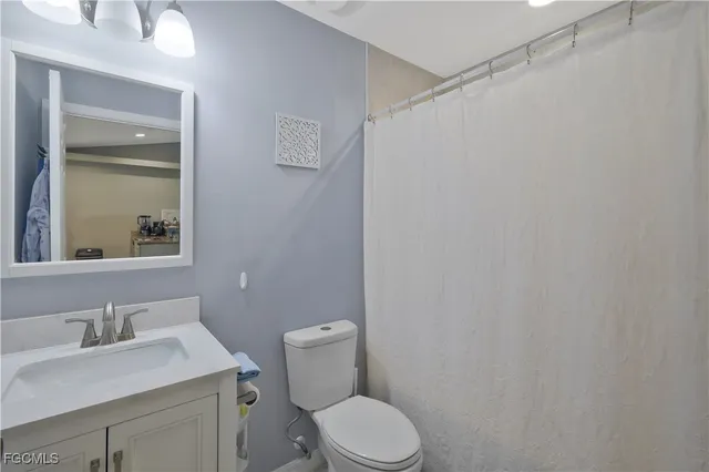 a bathroom with a granite countertop sink vanity mirror and toilet