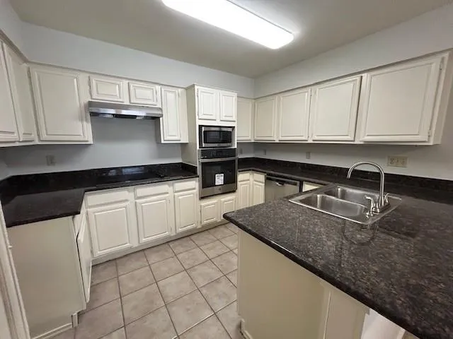 a kitchen with granite countertop a sink a stove and cabinets