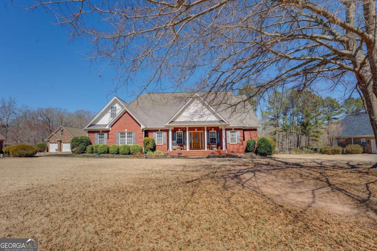 a front view of a house with a dirt yard and a large tree