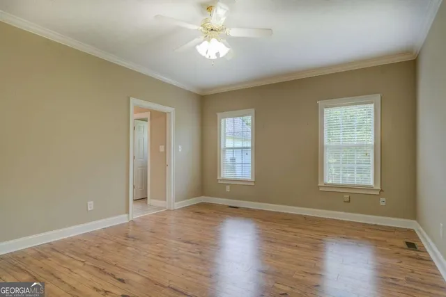 a view of an empty room with window and wooden floor