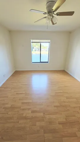 an empty room with wooden floor fan and windows