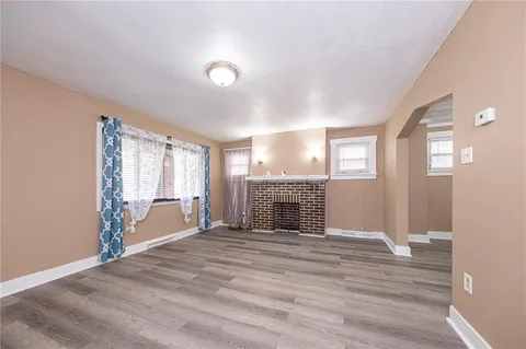an empty room with windows fireplace and wooden floor