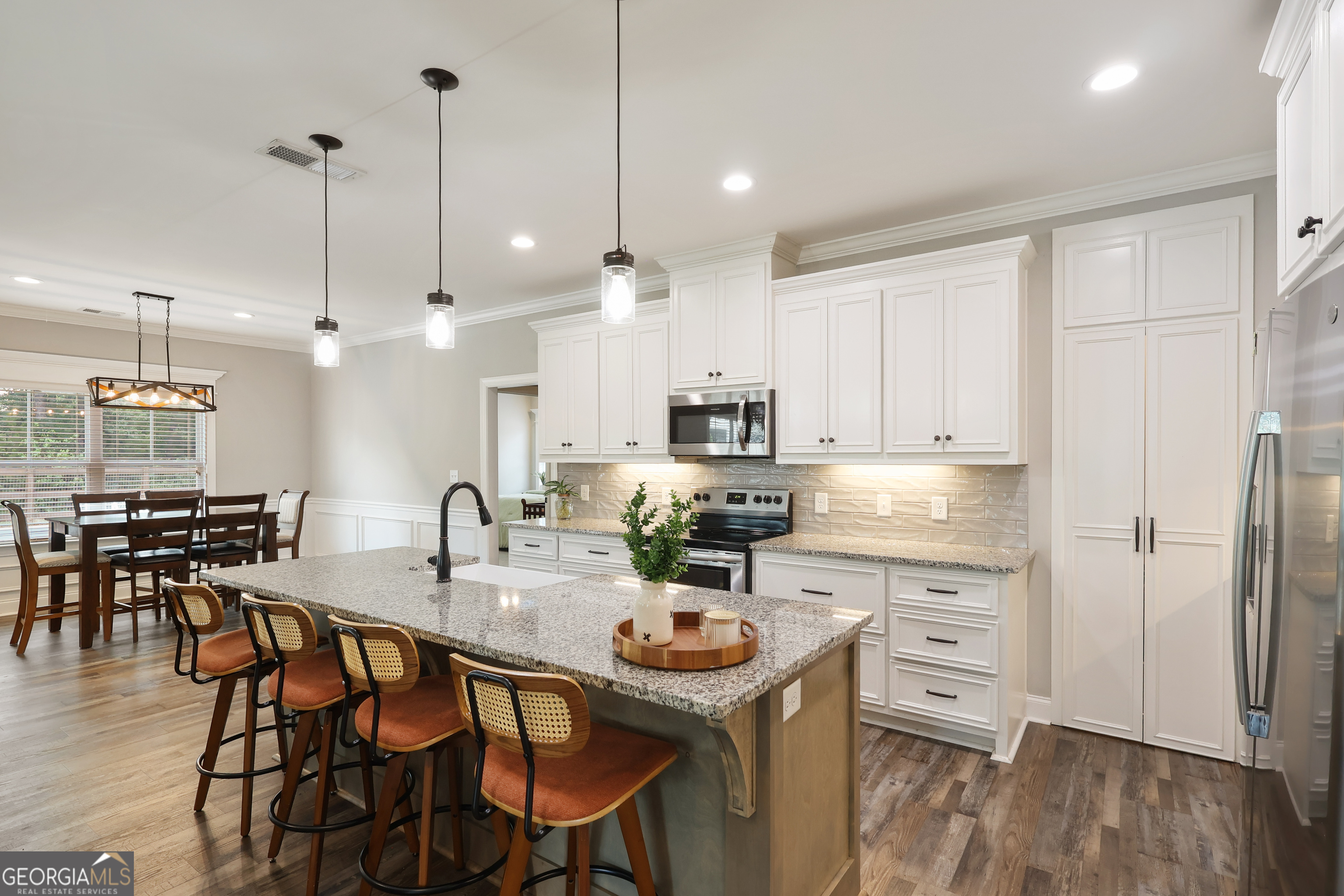 89 Claire Road Forsyth, GA 31029 - Photo 14 of 40 a kitchen with stainless steel appliances kitchen island granite countertop a dining table chairs stove and white cabinets