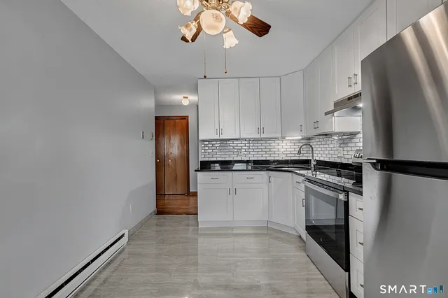 a kitchen with stainless steel appliances granite countertop a refrigerator a stove and a sink