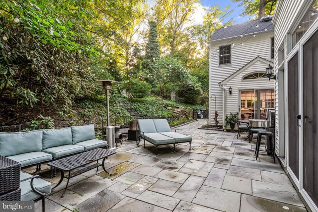 a view of a house with brick walls and a yard with plants and large trees