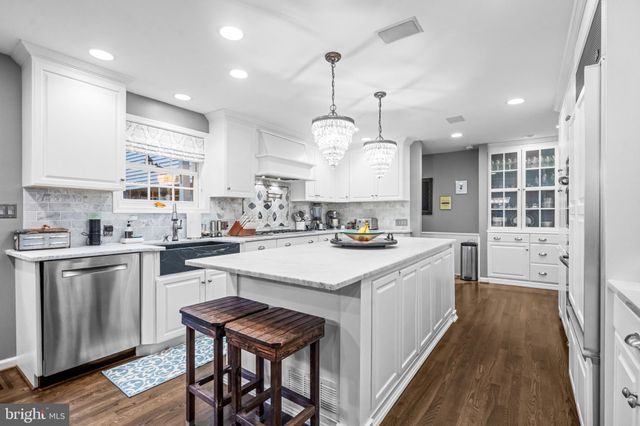 a kitchen with stainless steel appliances granite countertop a sink dishwasher a stove a refrigerator and island with wooden floor