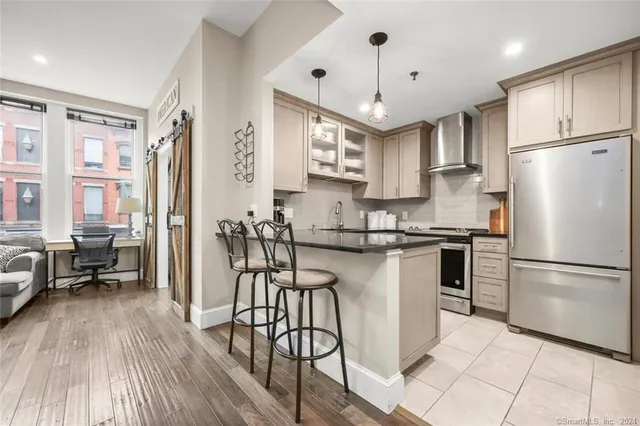 a kitchen with stainless steel appliances a refrigerator a stove a sink dishwasher and white cabinets with wooden floor