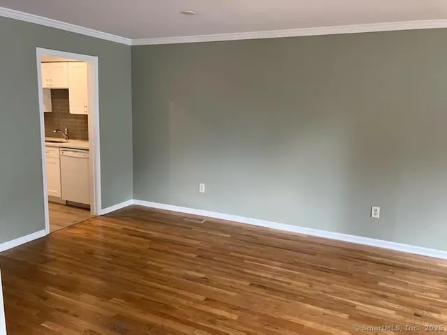 a view of an empty room with window and wooden floor