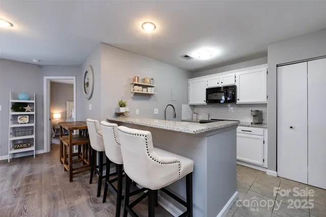 a kitchen with stainless steel appliances granite countertop a dining table chairs refrigerator and sink