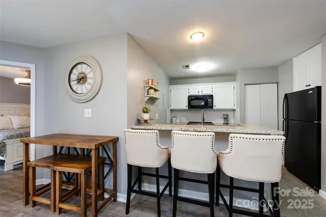 a kitchen with stainless steel appliances granite countertop a dining table chairs and a refrigerator