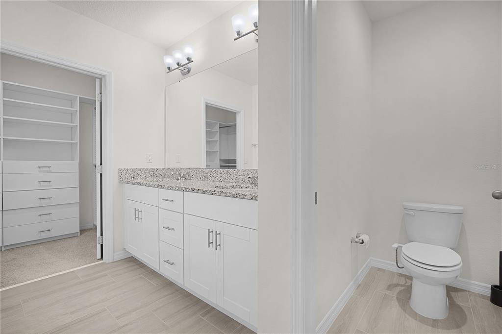 Undisclosed Address Winter Garden, FL 34787 - Photo 27 of 46 a bathroom with a granite countertop toilet a sink and a mirror