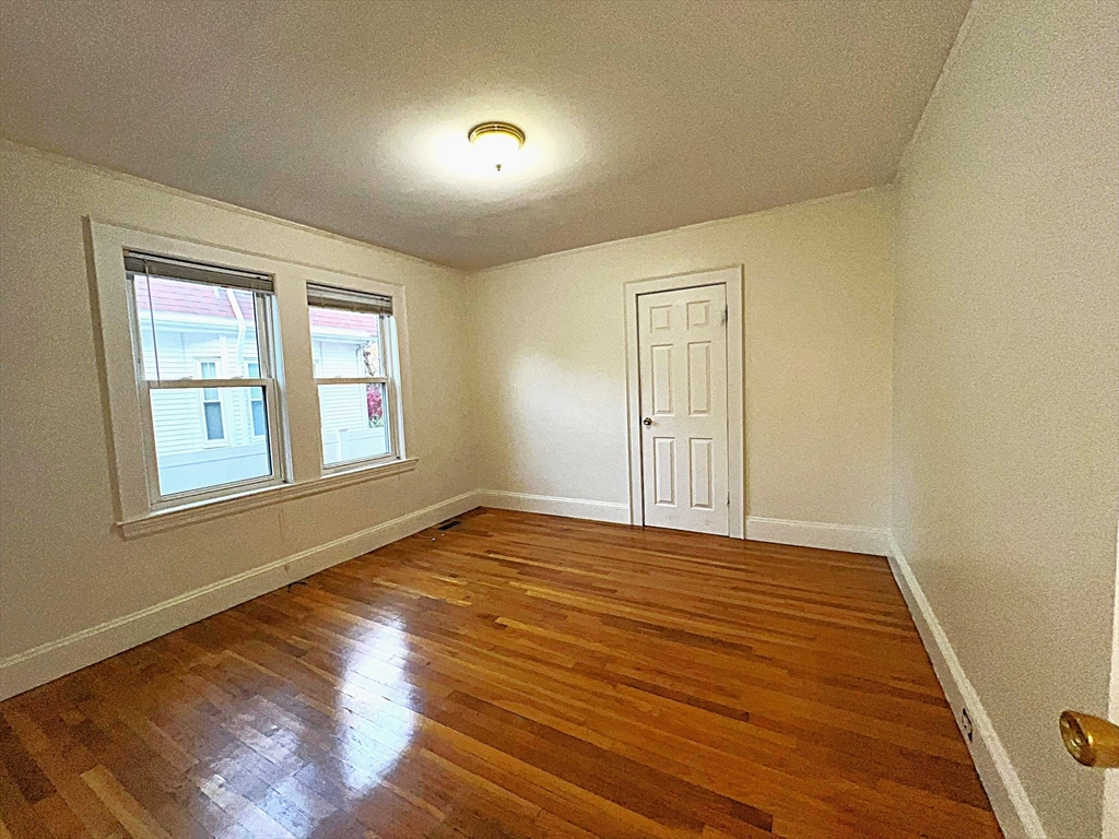 6 Oxford Avenue, Unit SIX Belmont, MA 02478 - Photo 8 of 13 a view of an empty room with wooden floor and a window