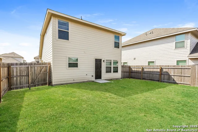 a view of backyard of house with wooden fence