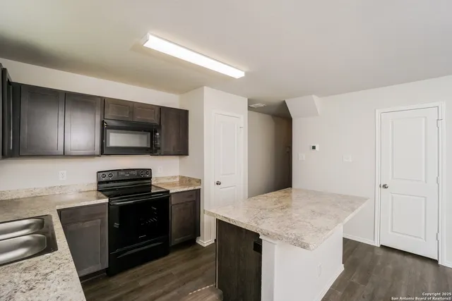 a kitchen with stainless steel appliances kitchen island granite countertop a stove and a microwave