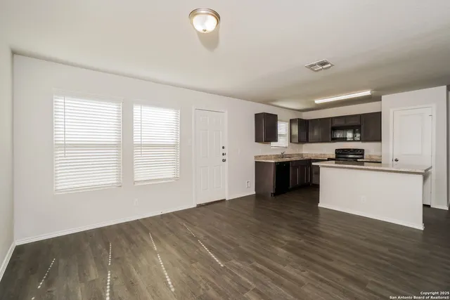 a view of kitchen with granite countertop stainless steel appliances stove sink and cabinets
