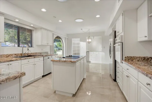 a kitchen with granite countertop a sink stove and refrigerator