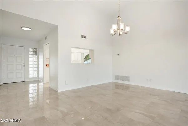 an empty room with chandelier fan and windows