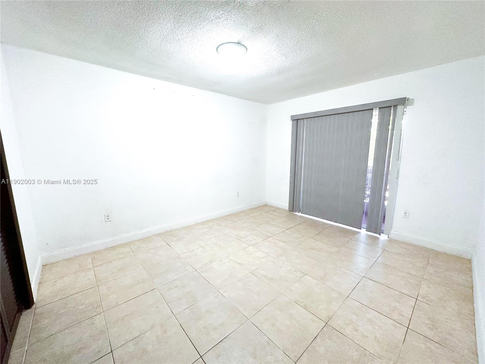 12275 Northeast 19th Avenue, Unit 6 North Miami, FL 33181 - Photo 11 of 12 an empty room with white walls and tiles