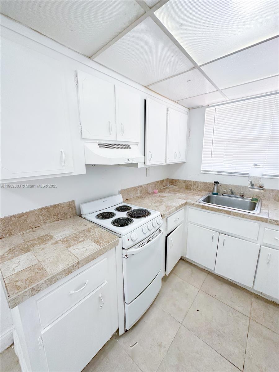 12275 Northeast 19th Avenue, Unit 6 North Miami, FL 33181 - Photo 5 of 12 a kitchen with granite countertop white cabinets and white appliances