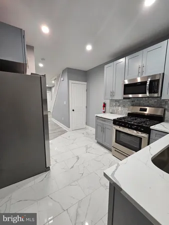 a kitchen with stainless steel appliances a stove a sink a microwave a refrigerator and cabinets
