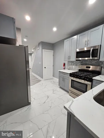 a kitchen with stainless steel appliances a stove a sink a microwave a refrigerator and cabinets