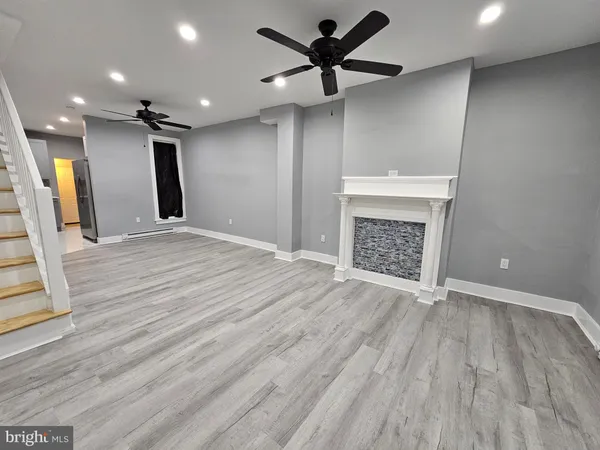 an empty room with wooden floor a ceiling fan and a fireplace