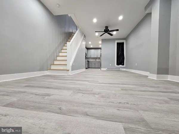 a view of an empty room with chandelier fan and wooden floor