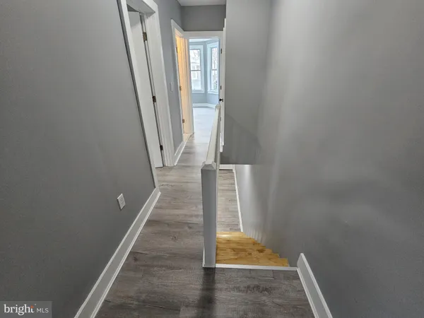 a view of an empty room with wooden floor and a ceiling fan
