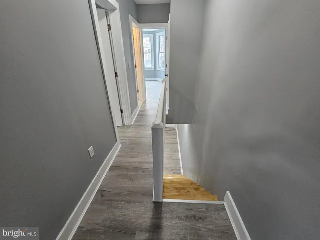 a view of an empty room with wooden floor and a ceiling fan