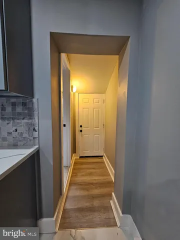 a view of a hallway with wooden floor and a bathroom