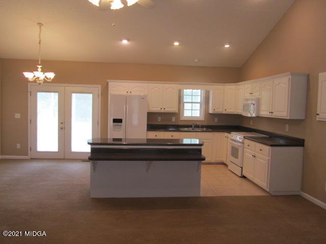 1383 Hamlin Road Lizella, GA 31052 - Photo 8 of 15 a large kitchen with granite countertop a stove top oven a sink a dining table and chairs
