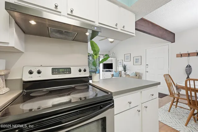 a kitchen with granite countertop a dining table chairs and white cabinets