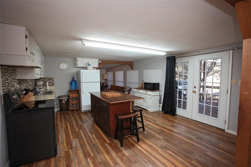 9051 Lacy Road Graford, TX 76449 - Photo 9 of 23 a kitchen with stainless steel appliances kitchen island granite countertop a refrigerator a stove a sink dishwasher and a dining table with wooden floor