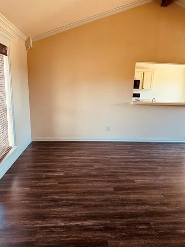 a view of an empty room with wooden floor fireplace and a window